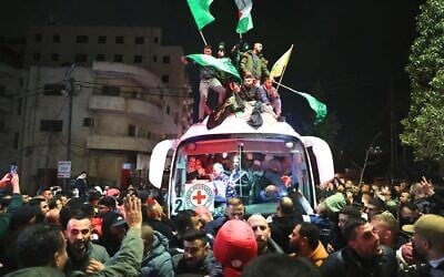 Des Palestiniens célèbrent la libération de quelque 90 prisonniers libérés par Israël à l'aube du 20 janvier 2025, à leur arrivée à bord d'un bus de la Croix-Rouge dans la ville palestinienne de Beitunia, en Cisjordanie, à la périphérie de Ramallah. (Crédit : Zain JAAFAR / AFP)