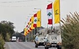 Des véhicules des Nations unies circulant sur une autoroute bordée de drapeaux libanais et du Hezbollah, dans la ville côtière de Naqura, dans le sud du Liban, à la frontière avec Israël, le 22 janvier 2025. (Crédit : Anwar Amro/AFP)