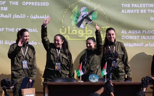 Les otages israéliennes Liri Albag, Karina Ariev, Daniella Gilboa, Naama Levy saluant sur une scène avant que des terroristes du Hamas ne les remettent à une équipe de la Croix-Rouge, dans la ville de Gaza, le 25 janvier 2025. (Crédit : AFP)