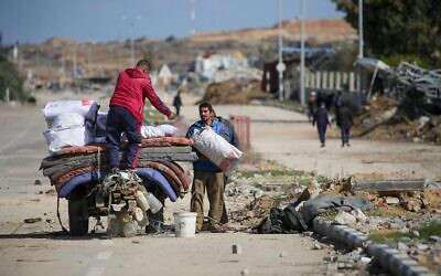 Des déplacés de Gaza chargeant un chariot avec leurs biens, près d'un barrage routier sur la rue Salah al-Din, à Nuseirat, le 25 janvier 2025. (Crédit : Eyad Baba/AFP)