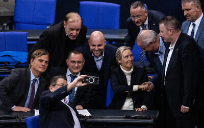 Des membres du parti d'extrême droite Alternative pour l'Allemagne (AfD), dont les codirigeants de l'AfD Alice Weidel (3eD) et Tino Chrupalla (2eL), se prennent en photo avec un téléphone portable alors qu'ils se réjouissent après un vote lors d'une session au Bundestag, la chambre basse du parlement, le 29 janvier 2025 à Berlin. (Crédit : John MACDOUGALL / AFP)