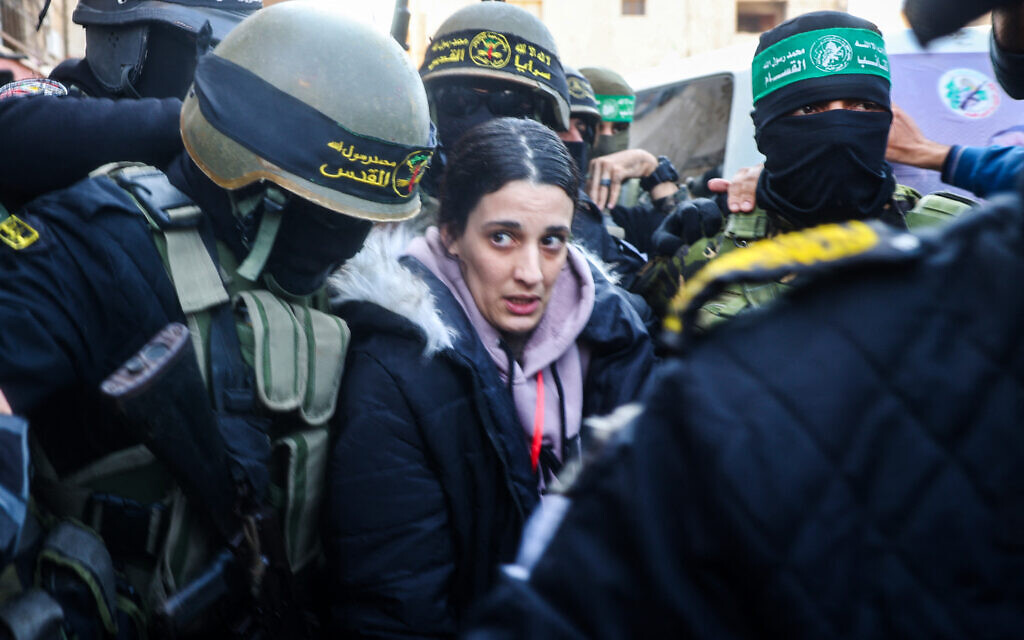 Des terroristes palestiniens du Jihad islamique et du Hamas escortent l'otage israélienne Arbel Yehud (au centre) pour la remettre à une équipe de la Croix-Rouge à Khan Younès, le 30 janvier 2025, dans le cadre de leur troisième échange d'otages contre des prisonniers. (Crédit : Eyad BABA / AFP)