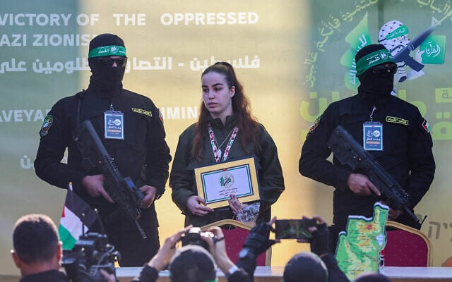 Des membres du Hamas escortent l'otage Agam Berger sur une estrade avant de la remettre à une équipe de la Croix-Rouge à Jabaliya le 30 janvier 2025, dans le cadre de leur troisième échange d'otages contre des prisonniers. (Crédit : Omar AL-QATTAA / AFP)