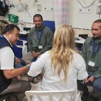 Deux otages thaïlandais récemment libérés discutent avec un officier thaïlandais, au centre à gauche, et le personnel médical à l'hôpital Shamir en Israël, le 26 novembre 2023. (Crédit : Ministère des affaires étrangères de Thaïlande via AP)