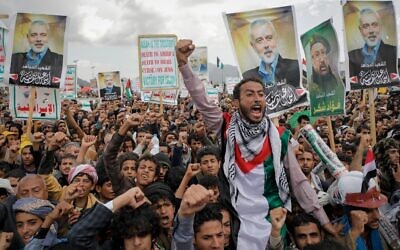 Des partisans houthis tenant des affiches montrant le chef du Hamas assassiné, Ismaïl Haniyeh, lors d'un rassemblement anti-Israël et anti-américain, à Sanaa, au Yémen, le 16 août 2024. (Crédit : Osamah Abdulrahman/AP)