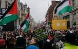 Des personnes brandissant des drapeaux et des pancartes lors d'une manifestation anti-Israël, à Westminster, à Londres, le 18 janvier 2025. (Crédit : Alberto Pezzali/AP)