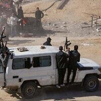 Des hommes armés du Hamas escortent les camions d'aide humanitaire qui entrent dans la bande de Gaza, à Rafah, le 21 janvier 2025, quelques jours après l'entrée en vigueur d'un accord de cessez-le-feu entre le Hamas et Israël. (Crédit : AP/Jehad Alshrafi)