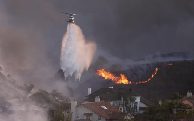 Un hélicoptère larguant de l'eau autour des maisons menacées par l'incendie de Palisades, à Pacific Palisades, en Californie, le 7 janvier 2025. (Crédit : David Swanson/AFP)