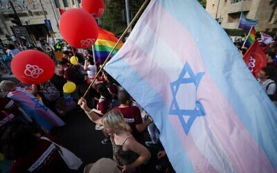 Une personne brandit un drapeau israélien sur lequel est superposé le drapeau de la fierté transgenre alors que des milliers de personnes participent à la marche des fiertés LGBTQ à Jérusalem, le 30 mai 2024. (Crédit : Yonatan Sindel/Flash90)