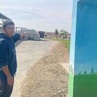 Korawit Kaeokoed, un ouvrier d'étable du kibboutz Alumim connu sous le nom de Kuay, pointe en direction de Gaza en décembre 2024, à l'extérieur de l'abri où nombre de ses collègues ouvriers agricoles thaïlandais ont été tués lors de l'attaque terroriste du Hamas le 7 octobre 2023. (Jessica Steinberg/Times of Israel).