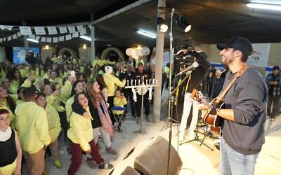 Le chanteur et acteur Idan Amedi, blessé alors qu'il était réserviste à Gaza, se produit dans le camp One Family, pour Hanoukka, devant des enfants touchés par le deuil, le 30 décembre 2024 (Autorisation)