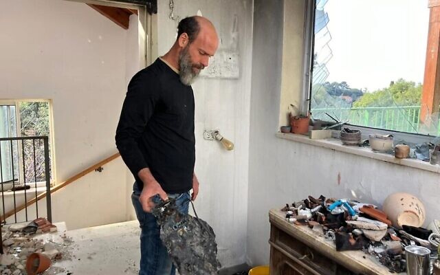 Ori Shaked tient dans sa main un aspirateur robot calciné dans sa maison du kibboutz Hanita, détruite par une roquette du Hezbollah tombée le 13 octobre 2023, le 6 janvier 2025. (Diana Bletter/Times of Israel)