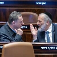 Le ministre de la Défense Israel Katz (à gauche) s'adresse au chef du Shas Aryeh Deri lors d'un vote à la Knesset le 31 décembre 2024. (Chaim Goldberg/Flash90)