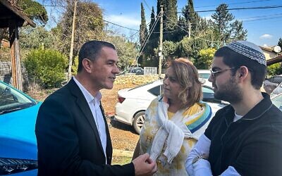 Le candidat à la mairie de Kiryat Shmona, Eli Zafrani (à gauche), s'entretenant avec deux habitants de la ville devant son QG de campagne le jour des élections, le 18 février 2025. (Crédit : Shalom Yerushalmi/Times of Israel)