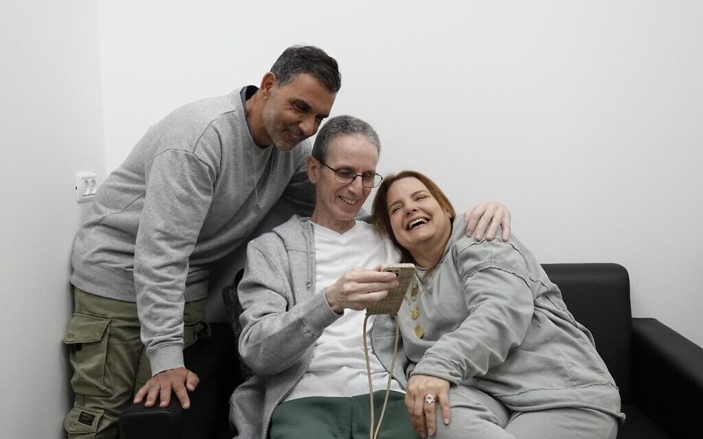 L'ex-otage Ohad Ben Ami retrouvant sa femme Raz et son frère Kobi dans un bâtiment de l'armée israélienne près de la frontière de Gaza, après 491 jours de captivité dans les geôles du Hamas, alors qu'ils passent un appel vidéo à ses trois filles, le 8 février 2025. (Crédit : Armée israélienne)