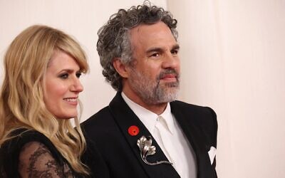 Sunrise Coigney, à gauche, et Mark Ruffalo à droite, qui porte un pin's représentant une main orange tenant un cœur, appelant à un cessez-le-feu à Gaza, assistent à la 96e cérémonie des Oscars à Hollywood, en Californie. Mark Ruffalo,  le 10 mars 2024 (Crédit : JC Olivera/Getty Images North America/Getty Images via AFP)