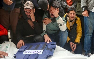 Des personnes endeuillées assistant aux funérailles de Gazaouis tués lors d'une frappe israélienne, à l'hôpital al-Awda du camp de réfugiés de Nuseirat, dans le centre de la bande de Gaza, le 26 décembre 2024. Israël a démenti les allégations selon lesquelles les cinq étaient des journalistes, affirmant qu'ils se faisaient passer pour des reporters mais étaient en réalité des terroristes du Jihad islamique palestinien. (Crédit : Eyad Baba/AFP)