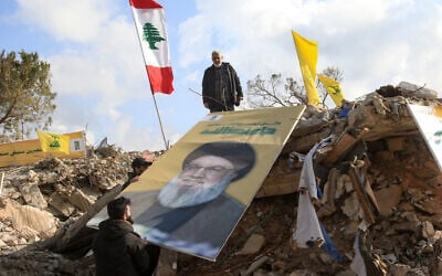 Des personnes plaçant une photo du chef du Hezbollah Hassan Nasrallah sur les décombres du sanctuaire de Shamoun al-Safa, dans le village de Shamaa à Tyr, dans le sud du Liban, le 31 janvier 2025. (Crédit : Mahmoud Zayyat/AFP)