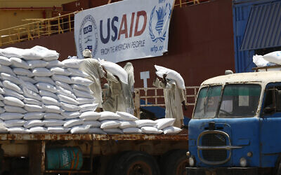 Des dockers soudanais déchargent des sacs de sorgho) de l'un des deux navires américains transportant des fournitures d'aide humanitaire fournies par l'agence de développement américaine USAID, à Port-Soudan, sur la côte de la mer Rouge, le 5 juin 2018. (Crédit : ASHRAF SHAZLY / AFP)