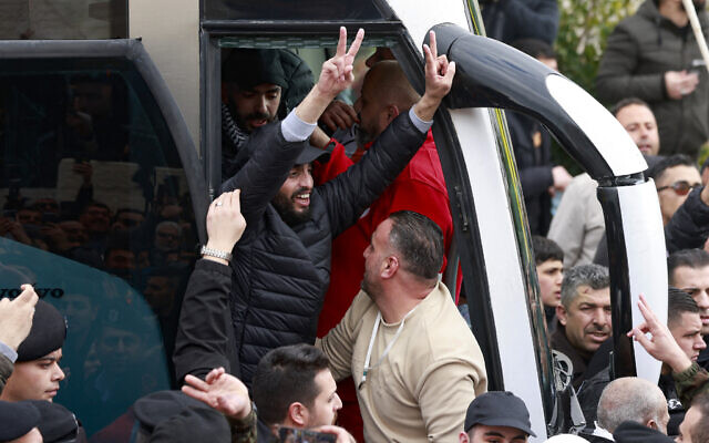 Un prisonnier palestinien libéré fait le signe de la victoire en sortant d'un bus à Ramallah, en Cisjordanie, le 8 février 2025. (Crédit :  Jaafar ASHTIYEH / AFP)