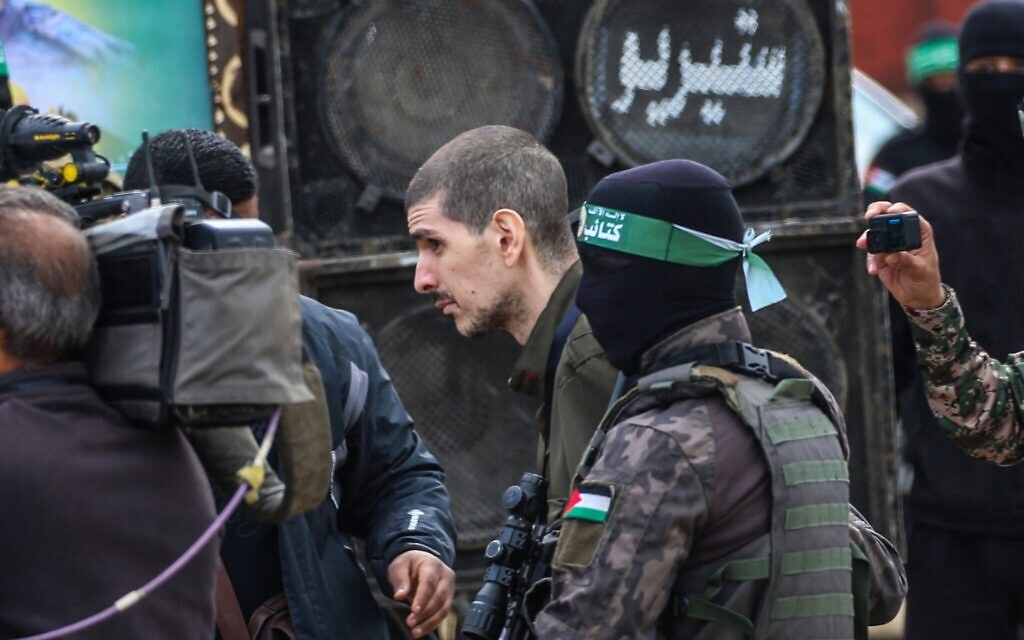 Des terroristes armés du Hamas escortant l'otage Or Levy avant de le remettre à une équipe de la Croix-Rouge, à Deir el-Balah, dans le centre de la bande de Gaza, le 8 février 2025. (Crédit : Eyad Baba/AFP)