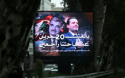La circulation se déroule derrière un panneau géant portant le portrait de l'ancien Premier ministre libanais Rafic Hariri (à gauche) et de son fils Saad Hariri, également ancien Premier ministre, dans le centre de Beyrouth, le 13 février 2025, à la veille du 20e anniversaire de l'assassinat de Rafic Hariri. (Photo de Joseph EID / AFP)