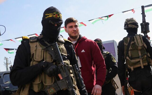 Un terroriste armé du Jihad islamique palestinien escortant l'otage Sasha Trupanov avant de le remettre à une équipe de la Croix-Rouge, à Khan Younès, dans le sud de la bande de Gaza, le 15 février 2025. (Crédit : Bashar Taleb/AFP)