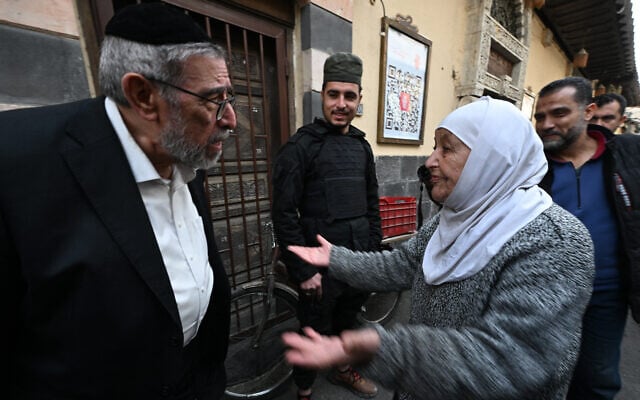 Une femme musulmane s'adresse au rabbin syrien Youssef Hamra, basé aux États-Unis, lors de sa première visite depuis le début des années 1990 à Damas, devant la synagogue Ifrange dans le quartier juif du district de Bab Sharqi, dans la capitale syrienne, le 19 février 2025. (Crédit : LOUAI BESHARA / AFP)