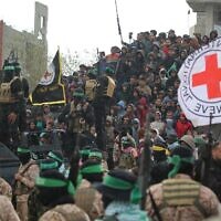 Une foule regardant des terroristes armés du Hamas remettre les corps de quatre otages israéliens à la Croix-Rouge, à Khan Younès, dans le sud de Gaza, le 20 février 2025. (Crédit : Eyad Baba/AFP)