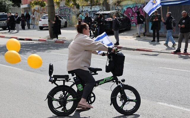 Une femme a attaché trois ballons orange à son vélo près de l'entrée de l'Institut médico-légal, à Tel Aviv, le 20 février 2025, en l'honneur de Shiri, Ariel et Kfir Bibas, trois otages israéliens, avant l'arrivée de leurs corps pour identification. (Crédit : Jack Guez/AFP)