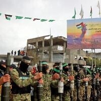 Des terroristes du Hamas lourdement armés se tiennent debout, alignés, sur lex lieux d'une remise d'otages israéliens à Rafah, dans le sud de la bande de Gaza, le 22 février 2025. (Omar AL-QATTAA / AFP)