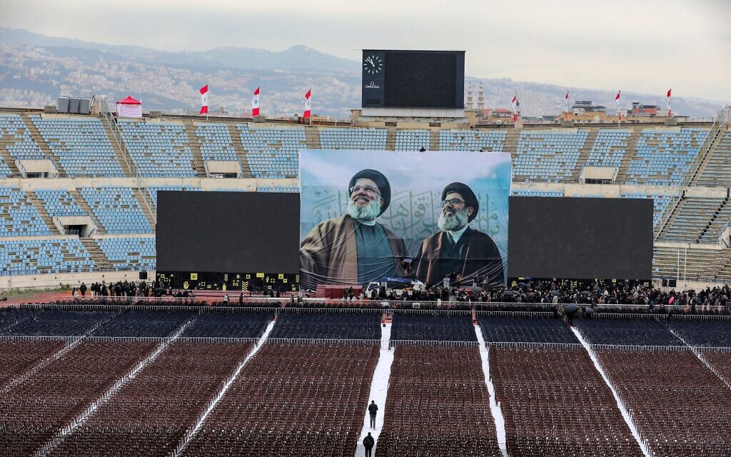 Un poster géant sur lequel apparaissent les portraits de l'ancien chef du Hezbollah tué par Israël Hassan Nasrallah (à gauche) et Hashem Safieddine, qui devait lui succéder mais a lui aussi été tué, au centre d'une scène faisant face aux gradins de la cité sportive Camil Chamoun de Beyrouth, le 22 février 2025, lors des préparatifs de la cérémonie en leur hommage. (Ibrahim AMRO / AFP)