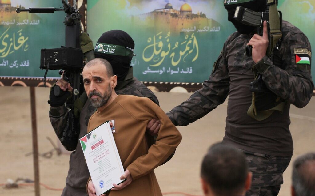 L'otage israélien Eli Sharabi, retenu par le Hamas à Gaza depuis le 7 octobre 2023, escorté par des terroristes armés du Hamas avant d'être remis à la Croix-Rouge, à Deir al-Balah, dans le centre de la bande de Gaza, le 8 février 2025. (Crédit : Abdel Kareem Hana/AP)