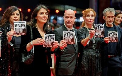 Des acteurs et actrices allemands tenant des photos de l'otage israélien David Cunio à leur arrivée à l'ouverture du Festival International du Film de Berlin, à Berlin, le 13 février 2025. (Crédit : Markus Schreiber/AP)