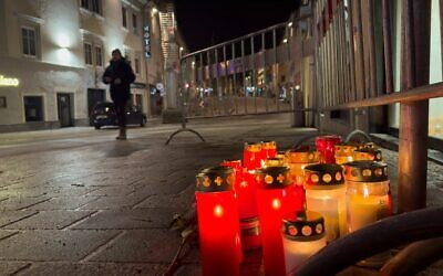 Un piéton passe devant des bougies sur le site d'une attaque au couteau à Villach, en Autriche, le 16 février 2025. (Crédit : AP Photo/Darko Bandic)