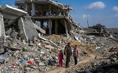 Un Palestinien et deux fillettes au milieu des décombres de maisons détruites pendant la guerre entre Israël et le Hamas dans le camp de réfugiés de Bureij, dans le centre de la bande de Gaza, le 17 février 2025. (Crédit : Abdel Kareem Hana/AP)
