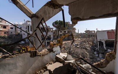 Un bulldozer équipé d'une perceuse travaille sur les ruines de maisons détruites par la guerre entre Israël et le  Hezbollah, dans la ville de Khiam, dans le sud du Liban, le 17 février 2025. (Crédit : Hassan Ammar/AP)