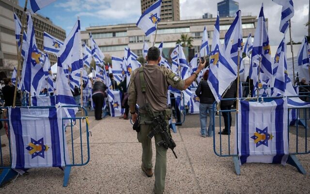 Un soldat israélien tenant son téléphone alors qu'il marche à travers la Place des Otages de Tel Aviv, le 20 février 2025, après que le groupe terroriste Hamas a restitué à Israël quatre corps d'otages, dont ceux d'une mère et de ses deux enfant, à la Croix-Rouge à Gaza. (AP Photo/Oded Balilty)