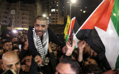 Zakaria Zubeidi, 49 ans, prisonnier palestinien et ancien haut commandant des Brigades des martyrs d'Al-Aqsa, libéré par Israël, agite un drapeau palestinien sous les acclamations de la foule après son arrivée à Ramallah, le 30 janvier 2025. (Crédit : AHMAD GHARABLI / AFP)