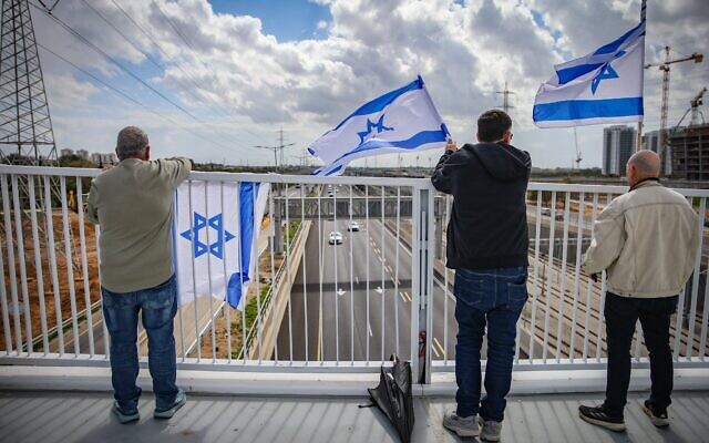 Des personnes rendant hommage en attendant un convoi avec les corps de quatre otages israéliens, près de Rishon Lezion, le 20 février 2025. (Crédit : Dor Pazuelo/Flash90)