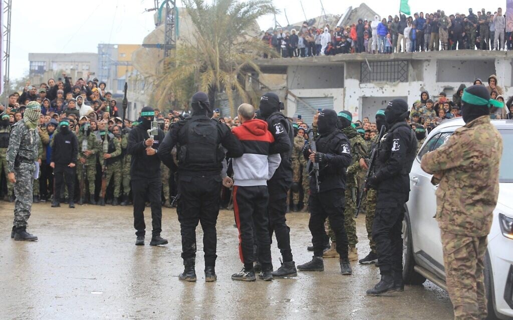 Des membres du Hamas défilent devant un otage israélien avant de le transférer à la Croix-Rouge, dans le cadre de l'accord de cessez-le-feu entre Israël et le Hamas, à Rafah, le 22 février 2025. (Abed Rahim Khatib/Flash90)