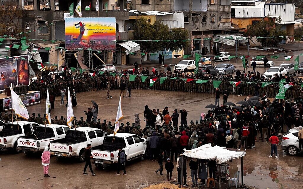 Des terroristes armés des Brigades Ezzedine al-Qassam montant la garde pendant que des Palestiniens attendent la remise des otages israéliens à la Croix-Rouge, à Rafah, le 22 février 2025. (Crédit : Saeed Mohammed/Flash90)