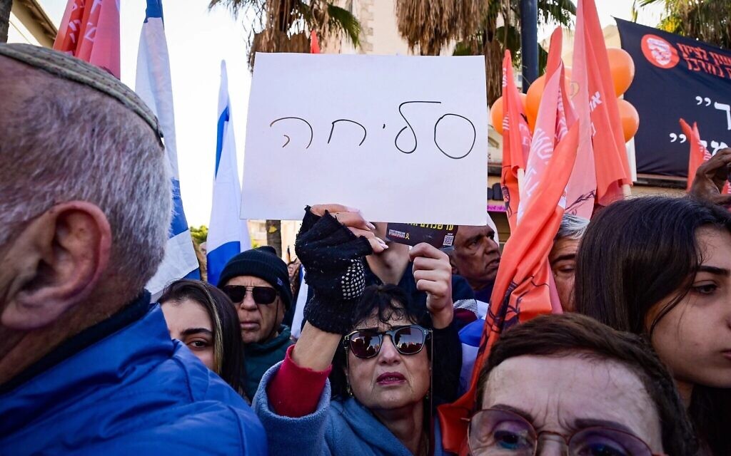 Une femme tient une pancarte sur laquelle est écrit « pardon » tandis que les gens rendent hommage aux otages assassinés Shiri Bibas et ses enfants Ariel et Kfir à Rishon LeZion, le 26 février 2025 (Crédit : Avshalom Sassoni/Flash90)