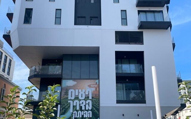 L'une des deux tours résidentielles de Tel Aviv abritant les résidents du kibboutz Reim évacués depuis 14 mois, avec une banderole indiquant « Reim sur le chemin du retour », le 14 janvier 2025. (Jessica Steinberg/Times of Israel)