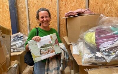 Reut Nechushtan tient l'un des draps importés vendus dans son entreprise de textiles d'intérieur, dans l'unité de stockage de Tel Aviv qu'elle loue après avoir été évacuée du kibboutz Reim le 8 octobre 2023. (Jessica Steinberg/Times of Israel)