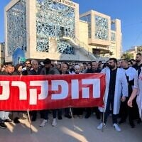Des manifestants tiennent une banderole qui dit « Nous avons été abandonnés », lors d'une marche pour protester contre les violences à l'encontre du personnel, le 4 février 2025. (Diana Bletter/Times of Israel)