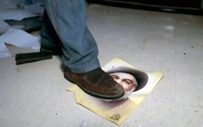 Un civil syrien marche sur une photo du défunt chef du Hezbollah Hassan Nasrallah laissée à l'ambassade d'Iran à Damas, en décembre 2024 (Capture d'écran/N12)