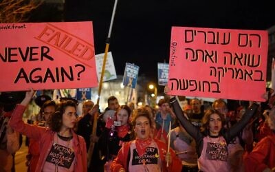 Lors d'une manifestation réclamant la libération des otages et des élections anticipées, un manifestant tient une pancarte en hébreu sur laquelle est écrit : "Ils vivent un holocauste et vous êtes en vacances en Amérique" en référence à la visite du Premier ministre Benjamin Netanyahu à Washington, à Tel Aviv, le 8 février 2025. (Crédit : Lior Segev/Mouvement de protestation pro-démocratie)