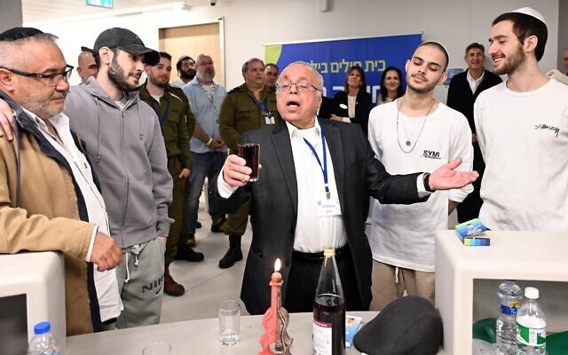 Aharon Rabi, le grand-père d'Eliya Cohen, l'otage libéré, dirige la prière de la Havdalah, qui marque la fin du sabbat juif, pour Cohen et ses compagnons d'infortune Omer Shem Tov et Omer Wenkert, à l'hôpital Beilinson, le 22 février 2025. (Crédit : Haim Zach/GPO)