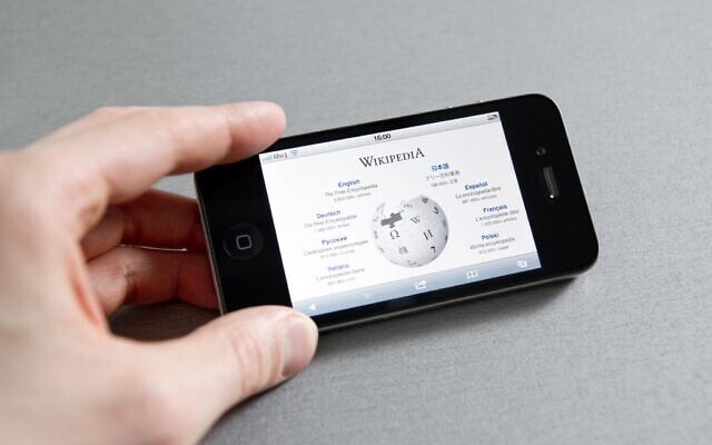 Illustration d'une personne consultant Wikipédia sur son téléphone. (Crédit : iStock/pressureUA)